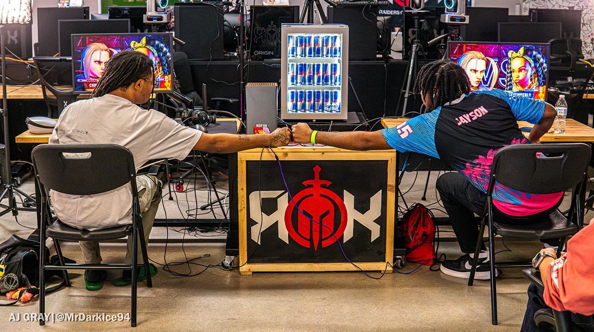 Two competitors exchanging a fist bump across the match station